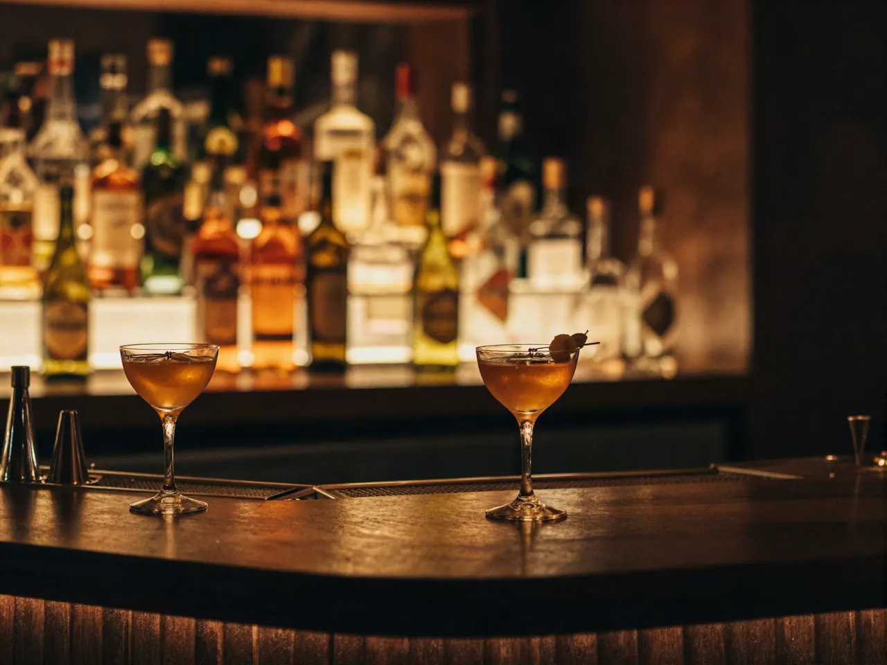 Barra del restaurante de noche con cocteles y botellas retroiluminadas