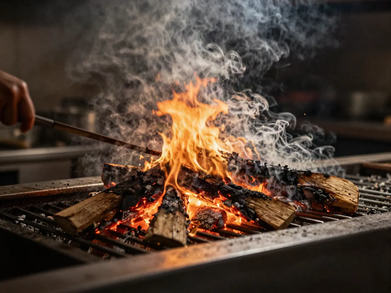 Cocinero trabajando sobre la parrilla de leña entre brasas