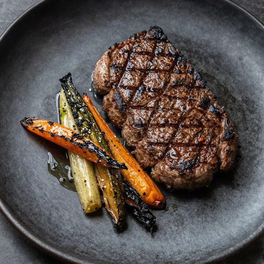 Corte de carne asada con vegetales carbonizados y aceite de hierbas